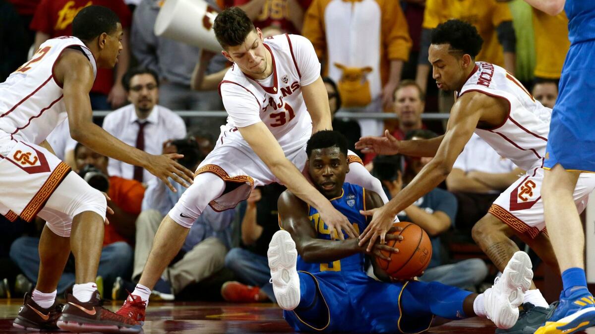UCLA guard Aaron Holiday scrambles to control the ball as USC's De'Anthony Melton, left, Nick Rakocevic and Jordan McGlaughlin, right, try to take it from him during second half action at the Galen Center.