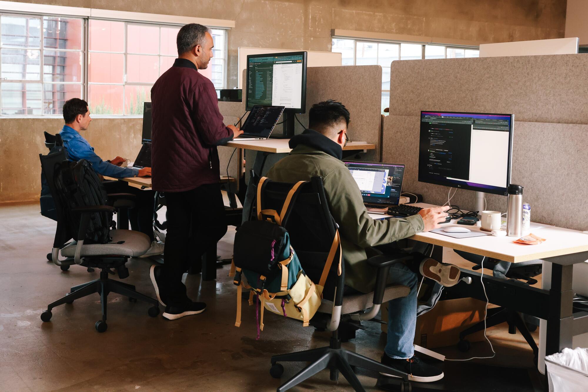 Three people at a row of workstations.