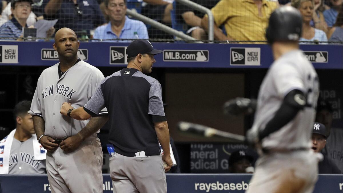 New York Yankees manager Aaron Boone, center, restrains starting pitcher CC Sabathia, left, after Tampa Bay Rays pitcher Andrew Kittredge threw behind Yankees batter Austin Romine, right, during the sixth inning.