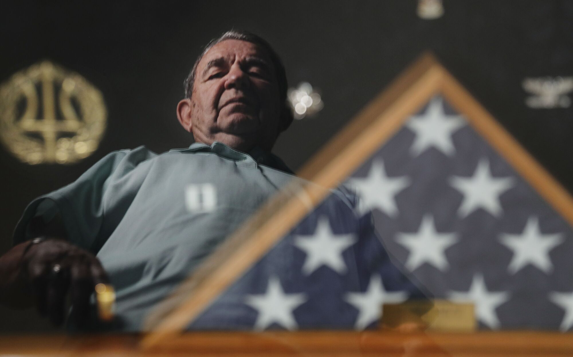 Navy Veteran Capt. John C. "Jack" Ensch is reflected in a glass case displaying a flag