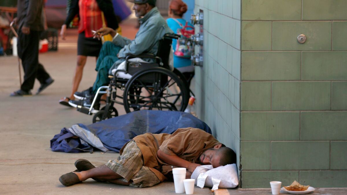 A man sleeps on the sidewalk in front of the Union Rescue Mission on skid row in downtown L.A. last month.