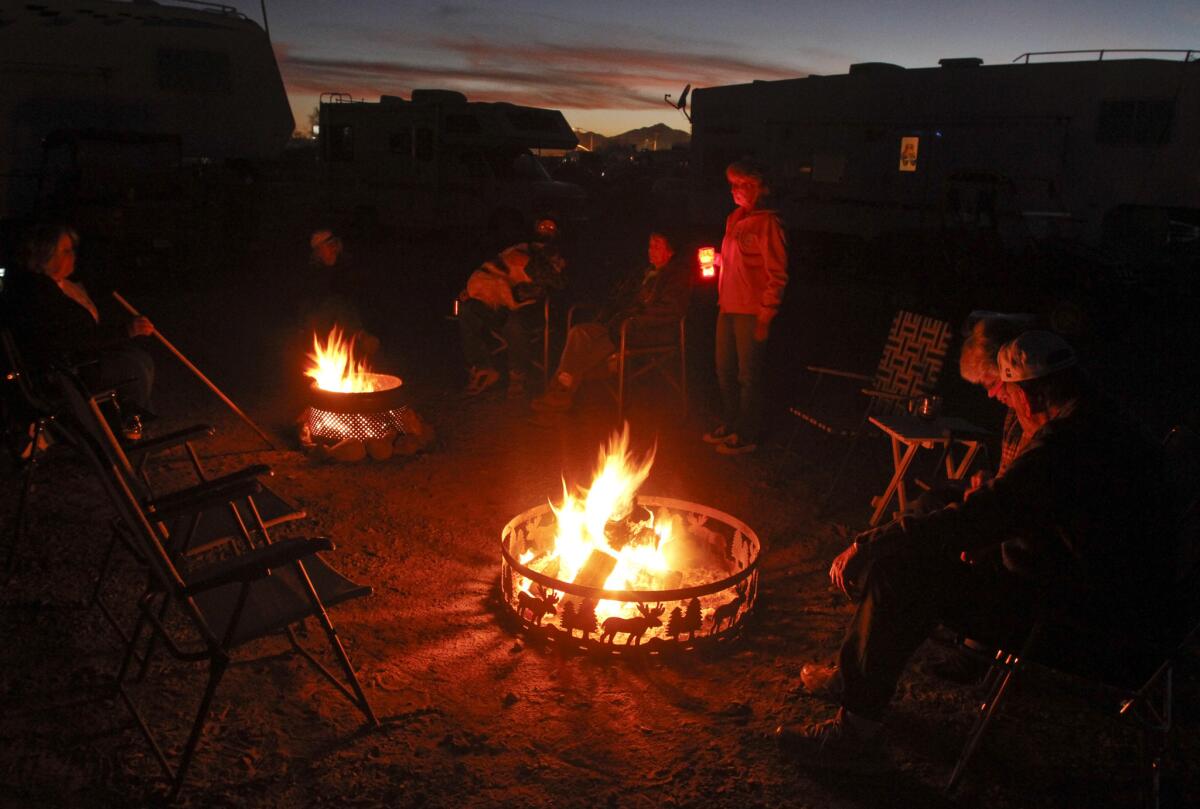 People gather around a fire at an motor home park in Quartzsite, Ariz.