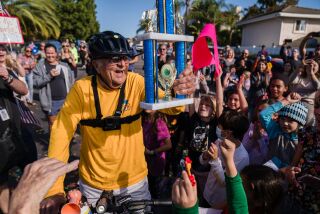Al Merritt, 83 years old, holds a trophy and to hundreds cheering him on after he rides his bicycle back home in Carlsbad on October 24, 2021. Merritt tracked his mileage everyday for the last 10 years with the goal of riding his bicycle so that's equivalent to him bicycling around the world. That's nearly 25,000 miles.