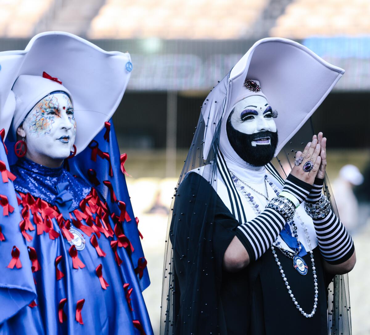 Two drag nuns smile and clap