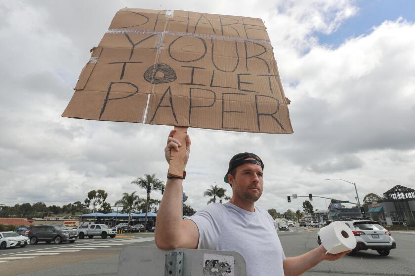 Encinitas resident Jonny Blue, 33, who is a physical therapist, makes a request for toilet paper so that he can in turn give it to drivers that need it while standing at the intersection of Encinitas Boulevard and El Camino Real on Saturday, March 14, 2020 in Encinitas, California. Blue said that after learning that friend of his, who has children, was unable to buy toilet paper due to people buying up large amounts of toilet paper because of the coronavirus, he decided to start a sort of free exchange of toilet paper in hopes that people of the community would share theirs with others who can't find any.