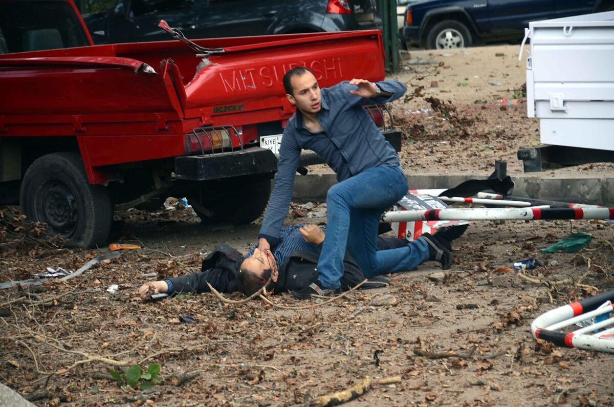 An Egyptian man aids one of the injured at the scene of a series of explosions near Cairo University.