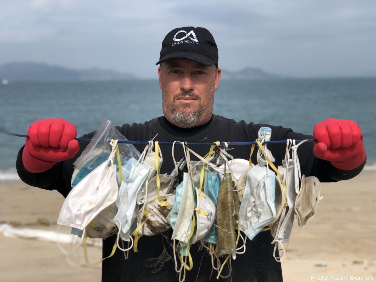 Environmental activist Gary Stokes displays dozens of discarded masks he collected from a Hong Kong beach in February.