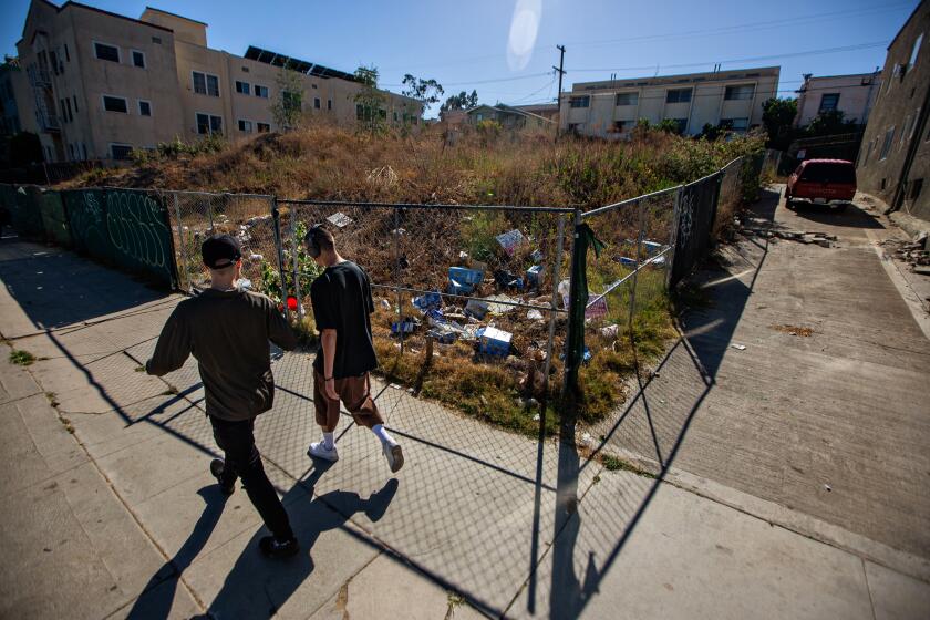 LOS ANGELES, CA - JUNE 10: People walk by an abandoned lot where MS-13 gang members killed several people near the intersection of Rampart Boulevard and Third Street on Thursday, June 10, 2021 in Los Angeles, CA. (Jason Armond / Los Angeles Times)