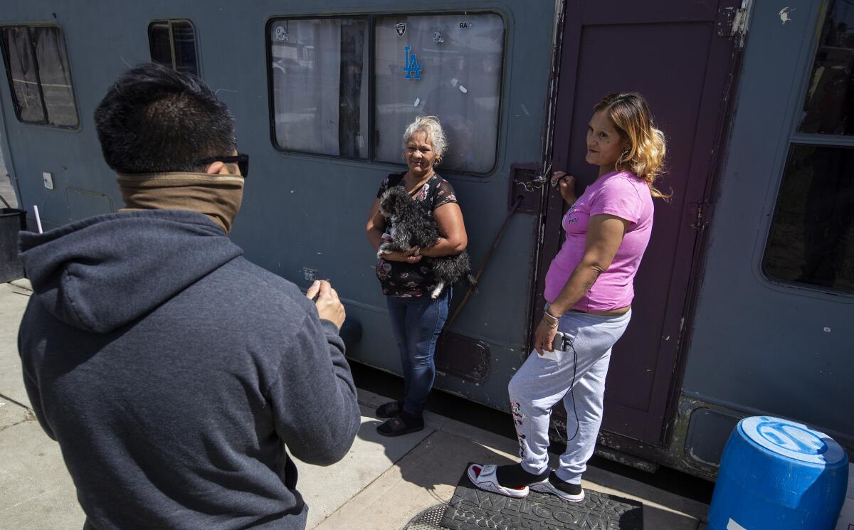 Three people outside a motorhome in South L.A.