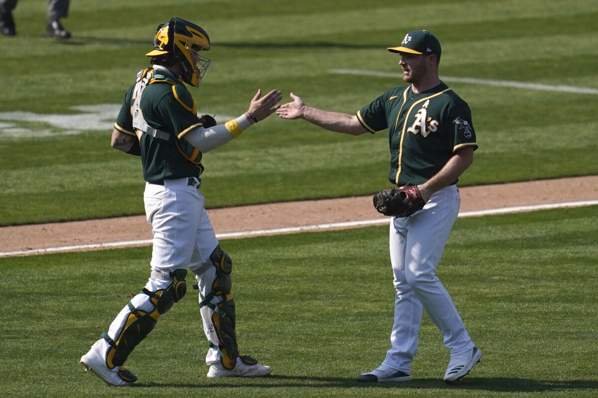 Oakland Athletics catcher Jonah Heim, left, celebrates with pitcher Liam Hendriks after the Athletics defeated the San Diego Padres in a baseball game in Oakland, Calif., Saturday, Sept. 5, 2020. (AP Photo/Jeff Chiu)