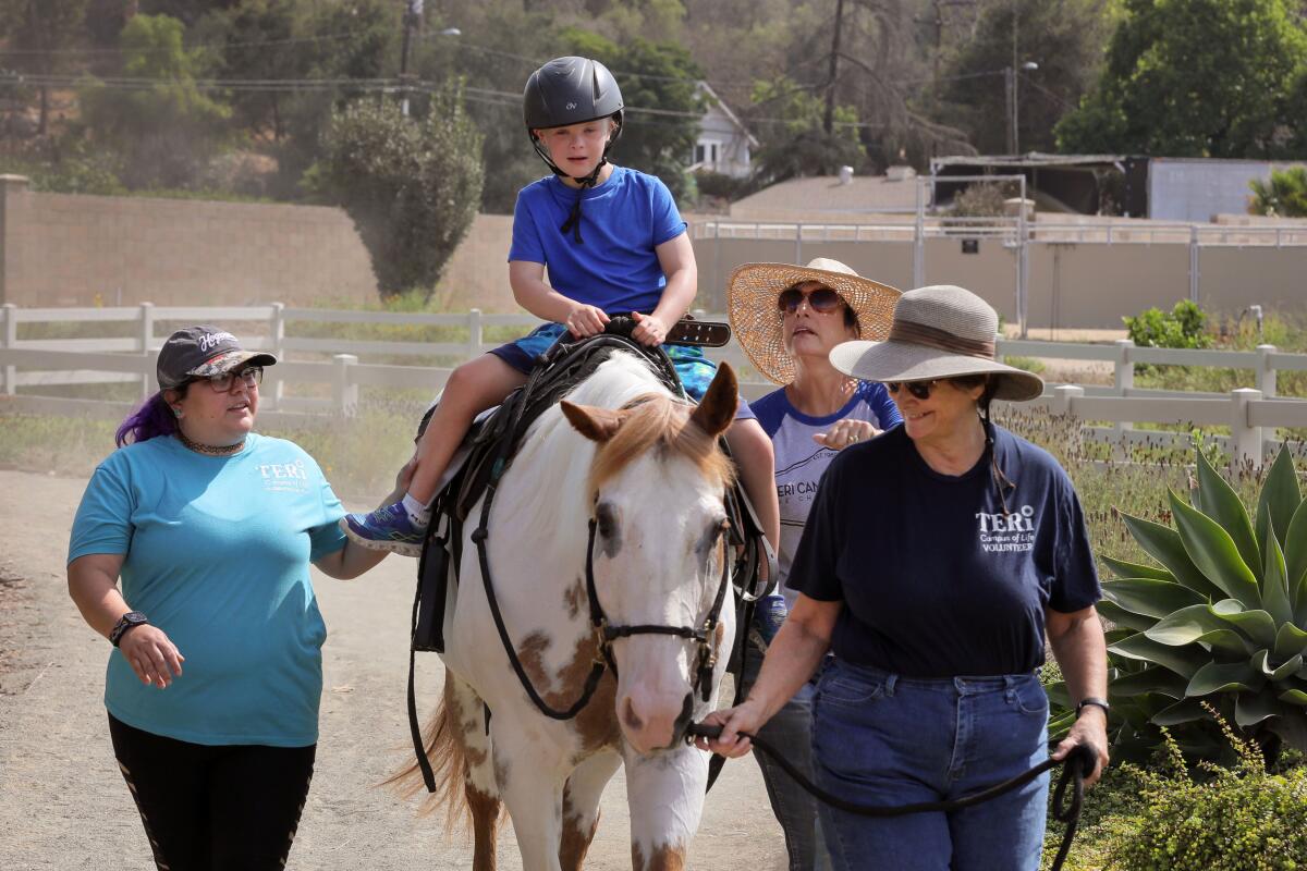 Teri Campus Of Life client Dylan Heald, 8, goes for a ride on Winnie the horse at the  therapeutic equestrian center.