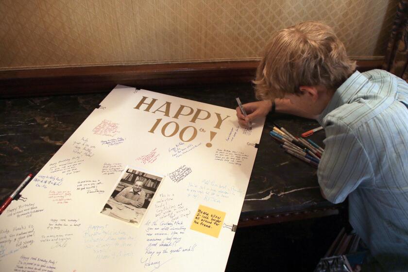 PASADENA, CA - JULY 21: Lev Marcus, 14, signs a card for his grandfather Nobel laureate Rudy Marcus who celebrated his 100th birthday with a day of festivities at the California Institute of Technology in Pasadena, CA on Friday, July 21, 2023. He is among the oldest living Nobel laureates - Henry Kissinger is a month older. He still works regularly and publishes research and gave up teaching only within the last few years. (Myung J. Chun / Los Angeles Times)
