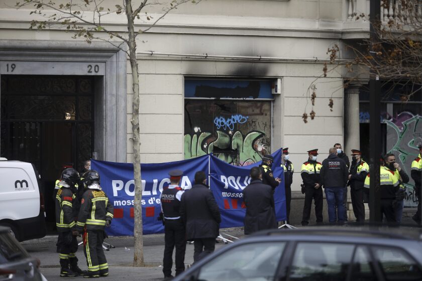 Policemen and firefighters work at the scene where a fire broke out in a building, in Barcelona, Spain, Tuesday, Nov. 30, 2021. A fire in part of a building occupied by squatters in central Barcelona has killed four members of the same family, including two adults and two children aged one and three, in the early hours of Tuesday. (Kike Rincon/Europa Press via AP)