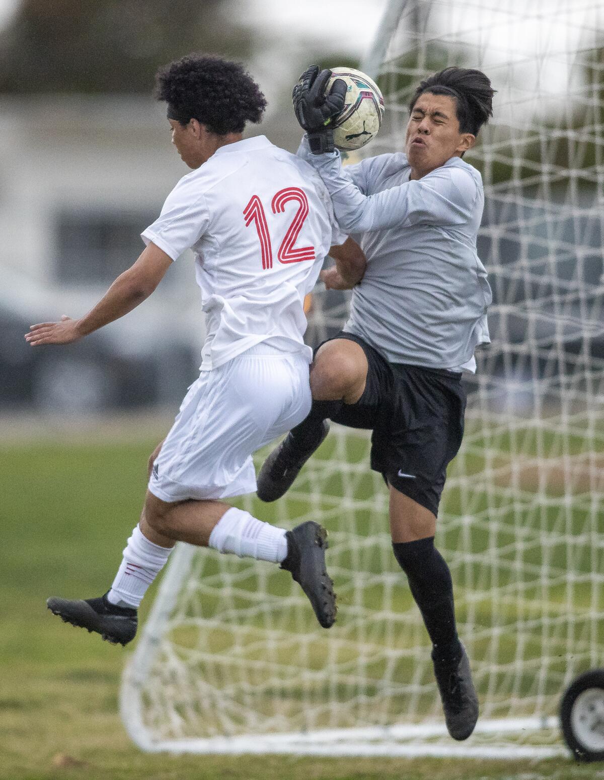 Estancia's John Uchityl goes up for a ball against Los Amigos' goalkeeper Jorge Sanchez during a nonleague match.