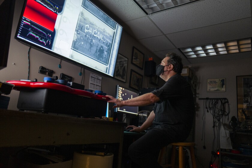 Dino Everett, archivero de la Universidad del Sur de California, mira una foto y cintas de rastreo en una pantalla grande.