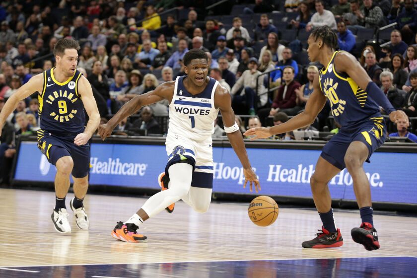 Minnesota Timberwolves guard Anthony Edwards (1) drives on Indiana Pacers guard T.J. McConnell (9) and Indiana Pacers guard Bennedict Mathurin (00) in the first quarter of an NBA basketball game Wednesday, Dec. 7, 2022, in Minneapolis. (AP Photo/Andy Clayton-King)
