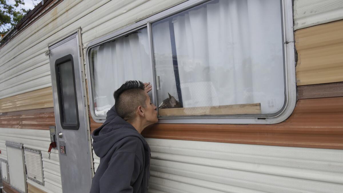 Shanna Couper Orona kisses her cat Maison through a window of her RV parked along a street in San Francisco. A federally mandated count of homeless in San Francisco increased 17% in two years, driven in part by a surge of people living in RVs and other vehicles.
