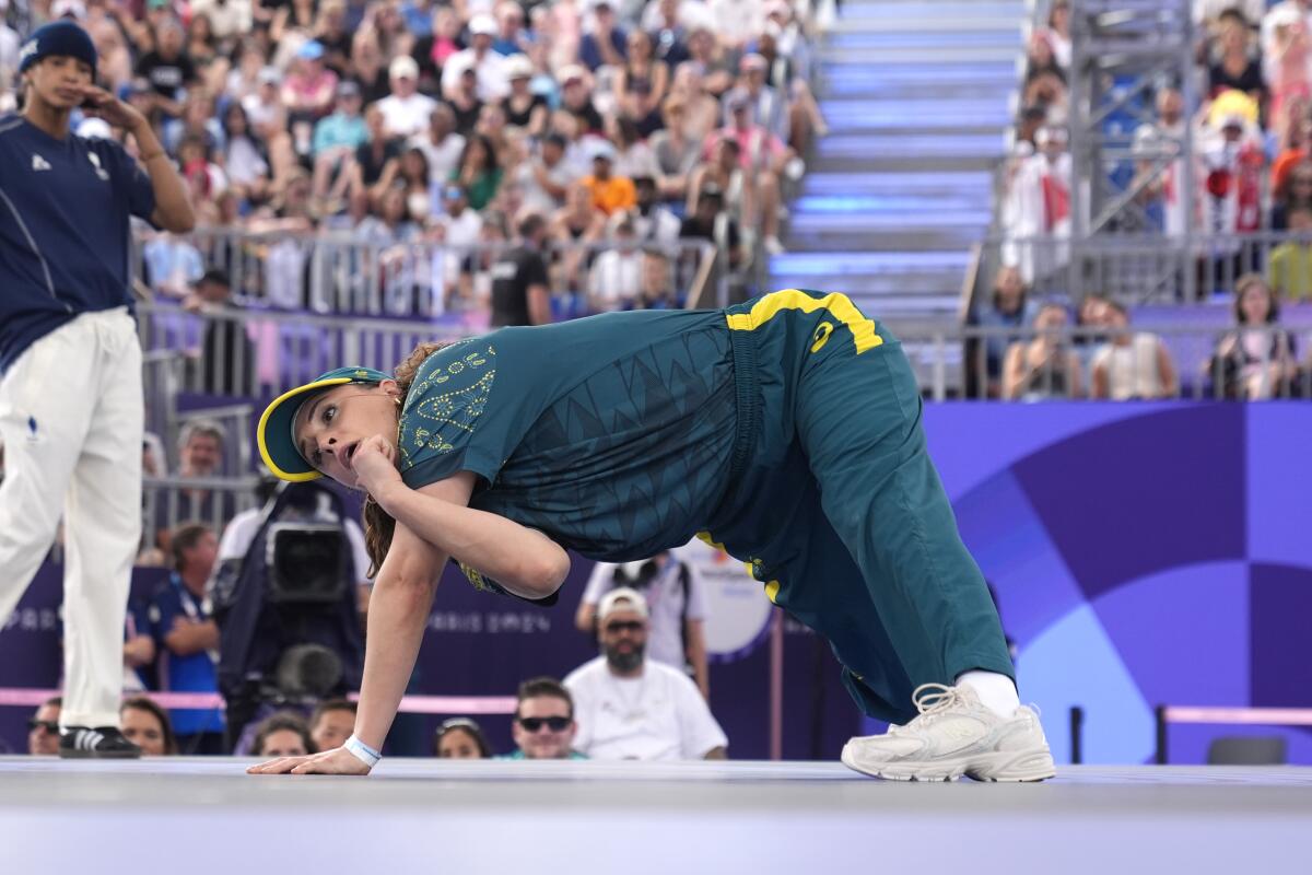 Australia's Rachael Gunn bent in a strange pose wearing a dark green tracksuit. 