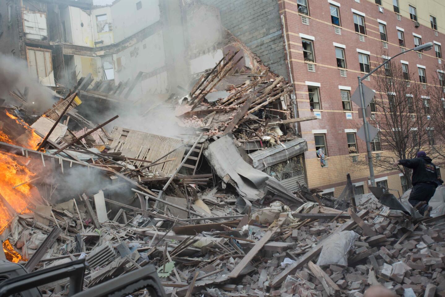 Emergency workers respond to the scene of an explosion and building collapse in the East Harlem neighborhood of New York on Wednesday. The explosion leveled an apartment building, and sent flames and billowing black smoke above the skyline.