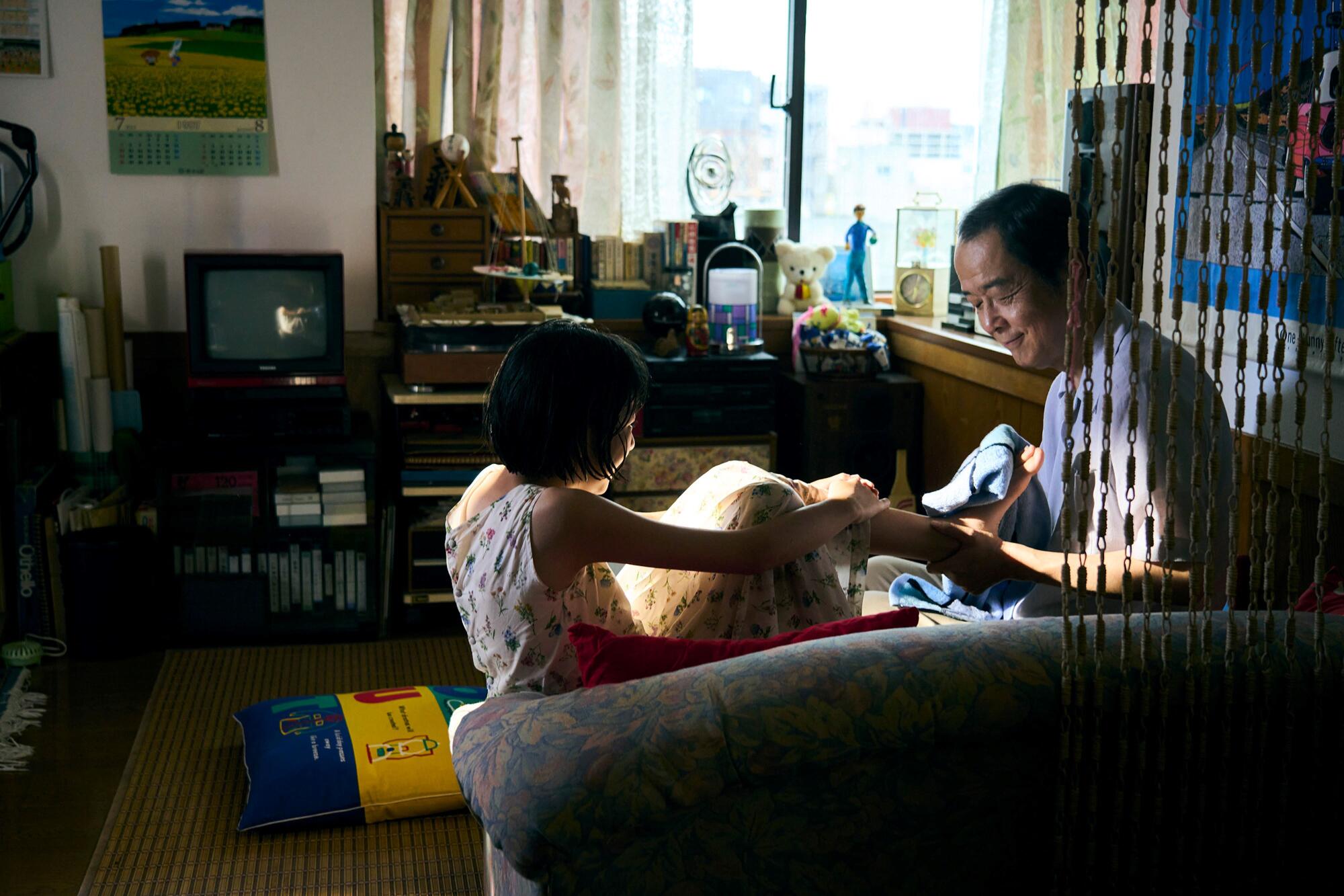 A daughter and father play together on a sofa.