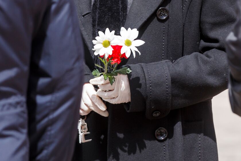 A man wearing gloves holds flower during the burial of a man who died of the new coronavirus at the South Municipal cemetery in Madrid, on March 23, 2020. - The coronavirus death toll in Spain surged to 2,182 after 462 people died within 24 hours, the health ministry said. The death rate showed a 27-percent increase on the figures released a day earlier, with the number of confirmed cases of COVID-19 rising to 33,089 in Spain, one of the worst-hit countries in the world after China and Italy. (Photo by BALDESCA SAMPER / AFP) (Photo by BALDESCA SAMPER/AFP via Getty Images)