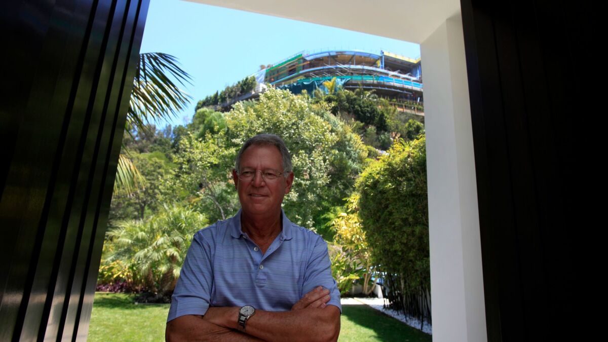 Joseph Horacek stands at the entrance to his Bel-Air home in 2014. Behind him, on the top of the hill, is the unfinished house on Strada Vecchia Road. (Francine Orr / Los Angeles Times)