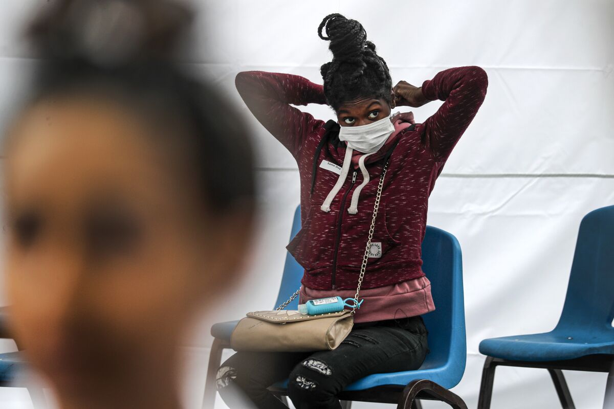 Precious Williams, 22, pregnant and suffering from cough and sore throat, puts on a face mask at a station set up for COVID-19 screening at Watts Health Center.