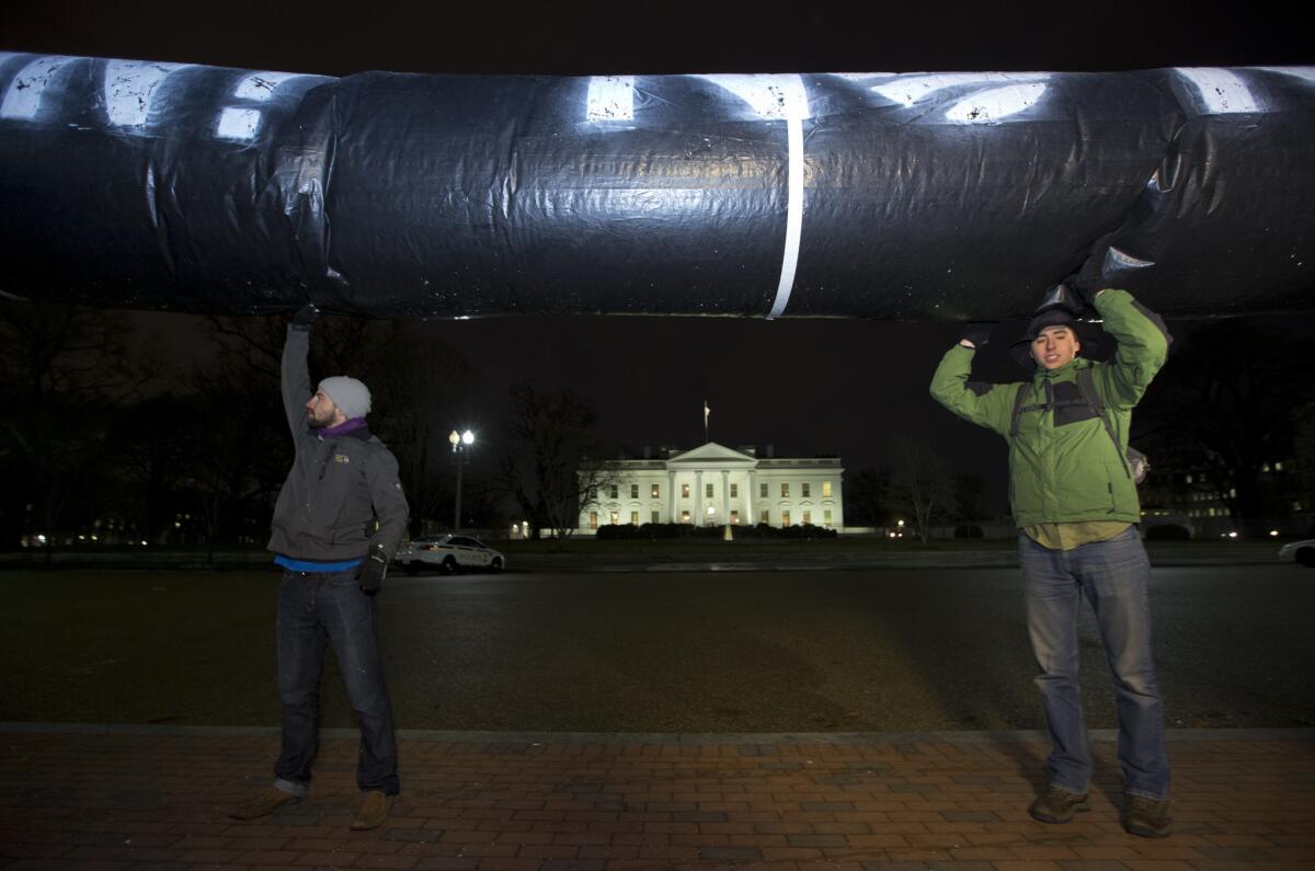 Activists hold up a substitute pipeline made of inflated black plastic during a protest vigil in Lafayette Park across from the White House in Washington, urging President Obama to reject the Keystone XL Pipeline following the release of the State Department's new environmental assessment.