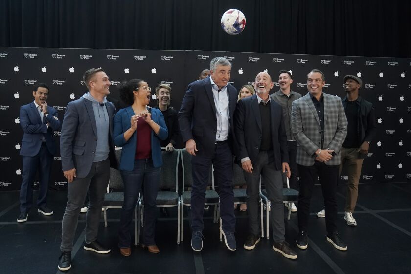 En foto del 10 de enero del 2023, el vicepresidente de servicios de Apple Eddy Cue salta para cebear el balón junto al comisionado de la MLS Don Garber durante el anuncio del Season Pass con Apple TV. (AP Foto/Jeff Chiu)