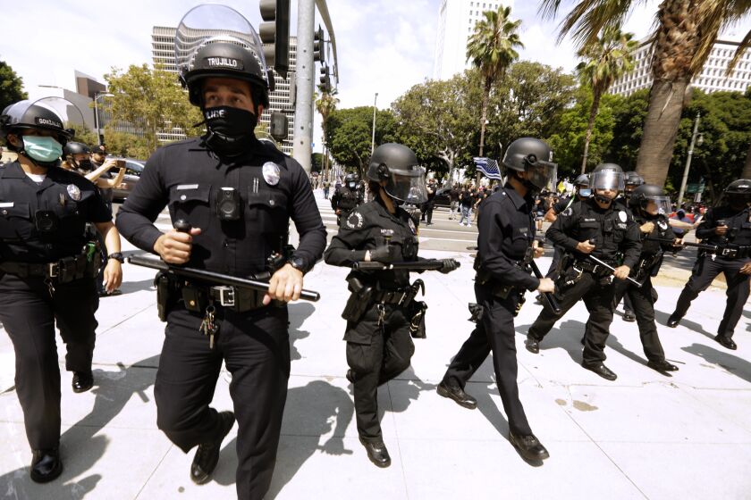 LOS ANGELES, CA - AUGUST 14, 2021 - - Los Angeles police officers go to separate advocates against vaccine mandates and pro-vaccine advocates in front of the L.A.P.D. Headquarters in downtown Los Angeles on August 14, 2021. A man was stabbed during the melee and taken by paramedics to a nearby hospital. No arrests were made in the confrontation. (Genaro Molina / Los Angeles Times)