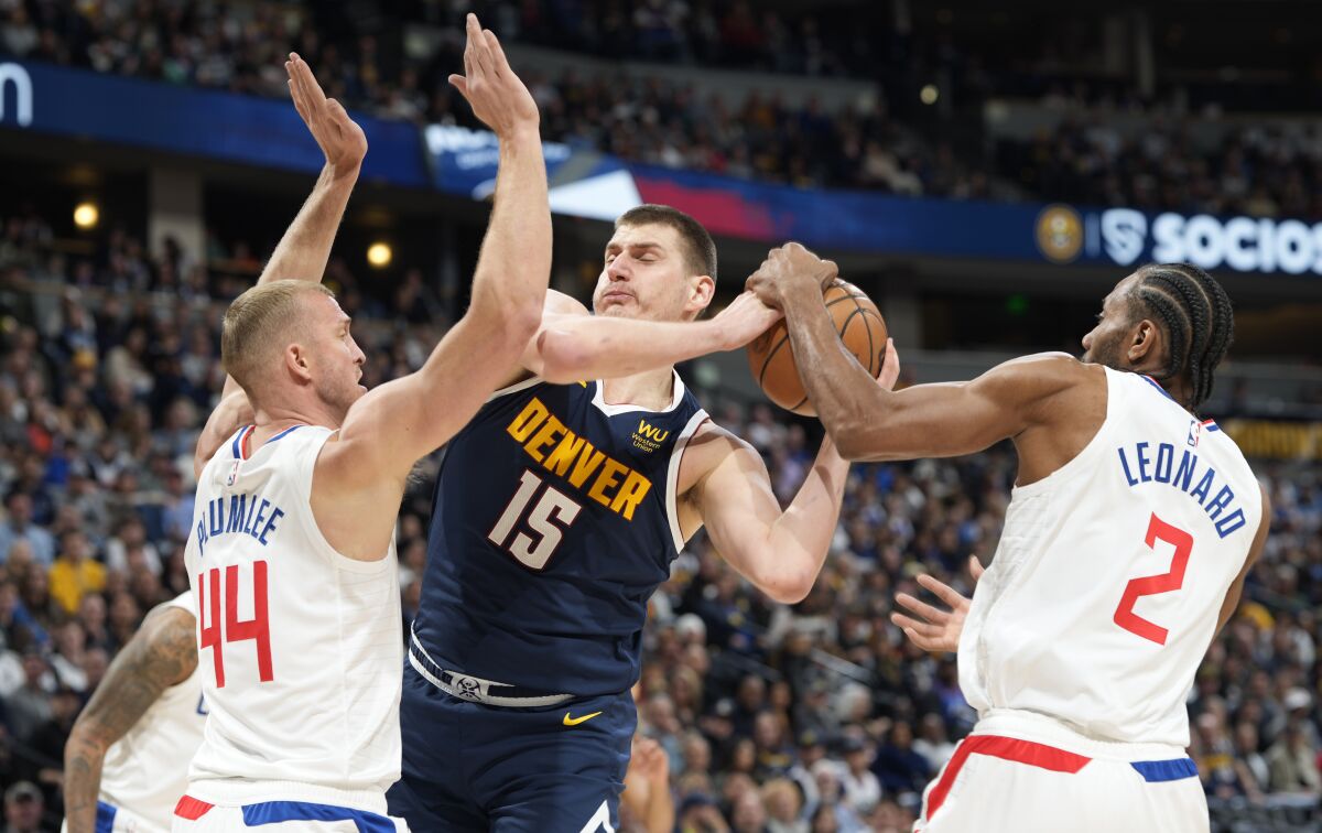 Denver Nuggets center Nikola Jokic hits the basket between Clippers center Mason Plumley and forward Kawhi Leonard.