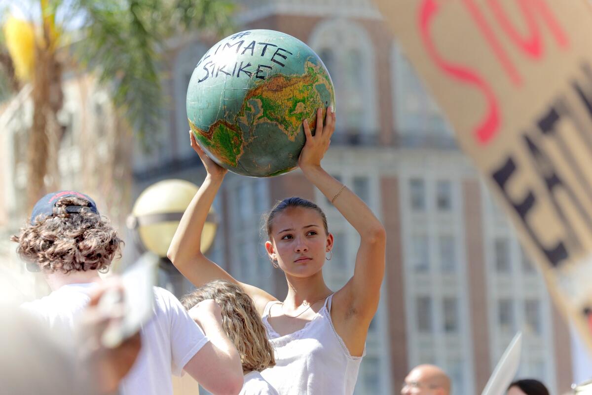 A young woman in L.A.'s Pershing Square holds a globe aloft during last fall's Global Climate Strike 