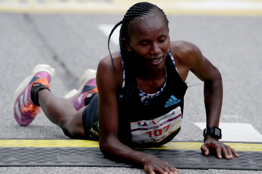 LOS ANGELES, CALIF. - MAR. 19, 2023. Stacy Ndiwa of Kenya collapses after crossing the finish line to win the women's elite Los Angeles Marathon on Sunday, Mar. 19, 2023 (Luis Sinco / Los Angeles Times)