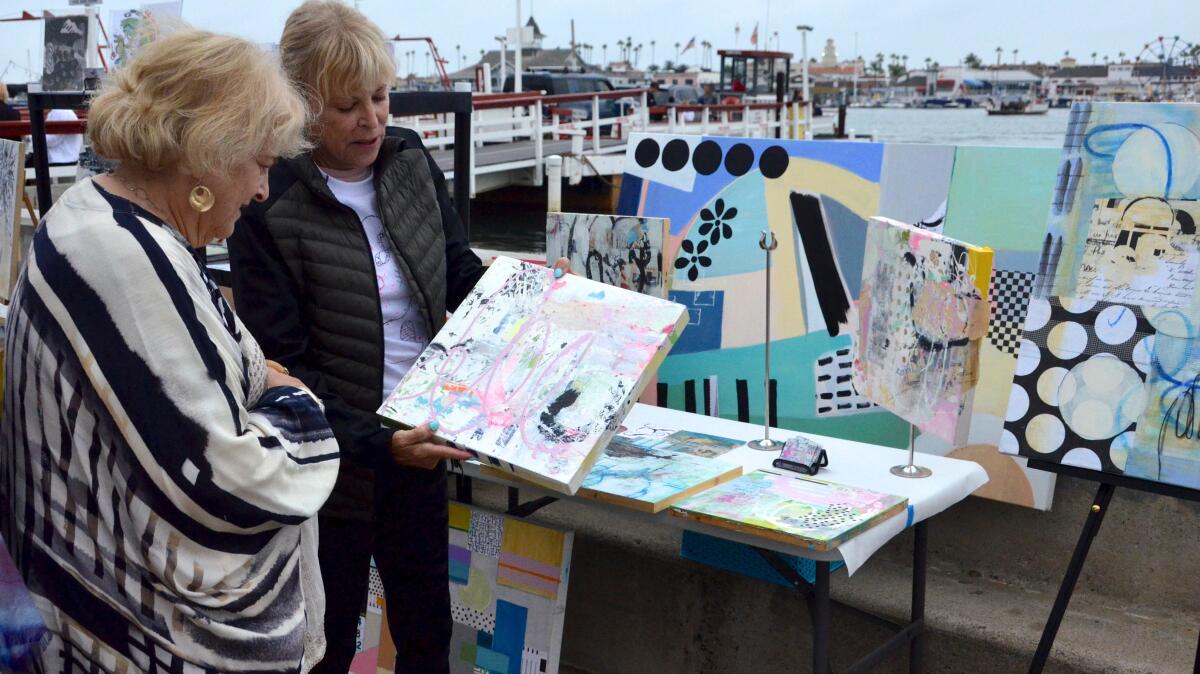 Mixed-media artist Karen Stein explains her multilayered process to a Balboa Island ArtWalk attendee on Sunday.