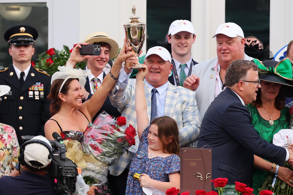 Trainer Kenny McPeek raises the trophy after winning this year’s Kentucky Derby with Mystik Dan.