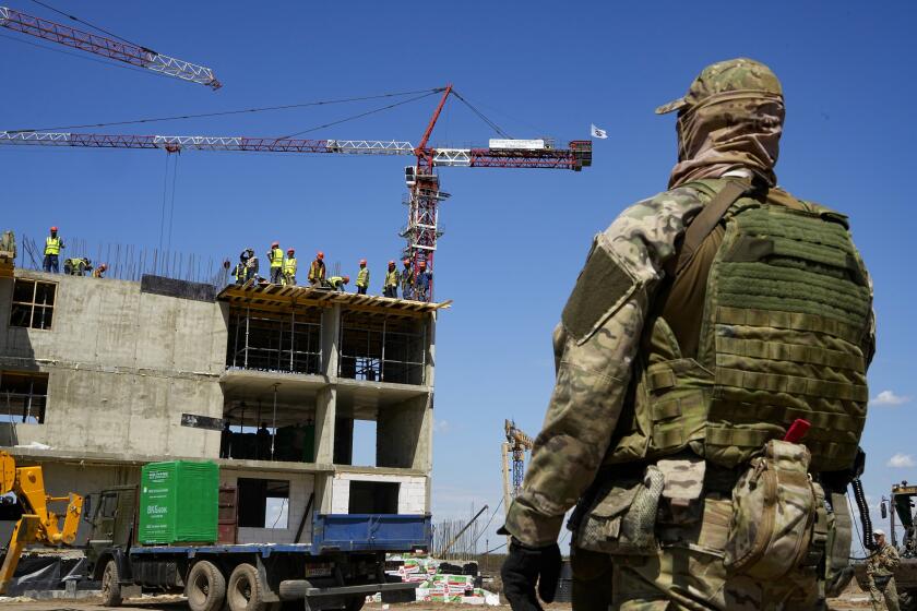 FILE - A Russian soldier guards the site of a new apartment building which is is being built with the support of the Russian Defense Ministry, in Mariupol, in territory under control of the government of the Donetsk People's Republic, in eastern Ukraine, Wednesday, July 13, 2022. This photo was taken during a trip organized by the Russian Ministry of Defense. (AP Photo/File)