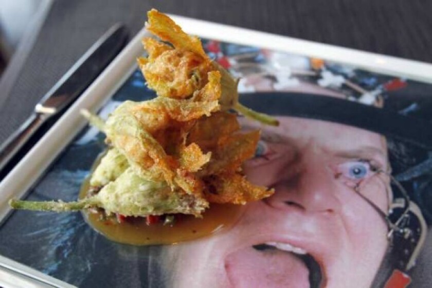 Flor de calabaza tempura is fried squash blossoms with Spanish bacalao, veal reduction, chorizo jus, capers and olives. It's served on a plate decorated with a photo from "A Clockwork Orange."