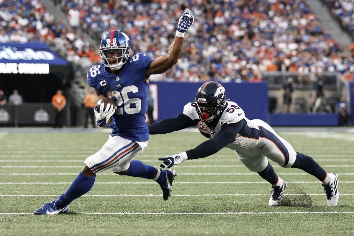New York Giants running back Saquon Barkley (26) runs away from Denver Broncos' Von Miller (58) during the second half of an NFL football game Sunday, Sept. 12, 2021, in East Rutherford, N.J. The Broncos won 27-13. (AP Photo/Adam Hunger)