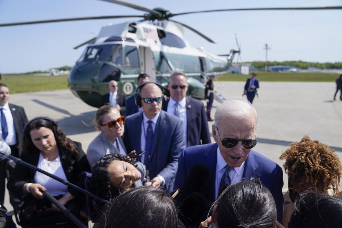 A man in sunglasses talks to other people near a helicopter outdoors.