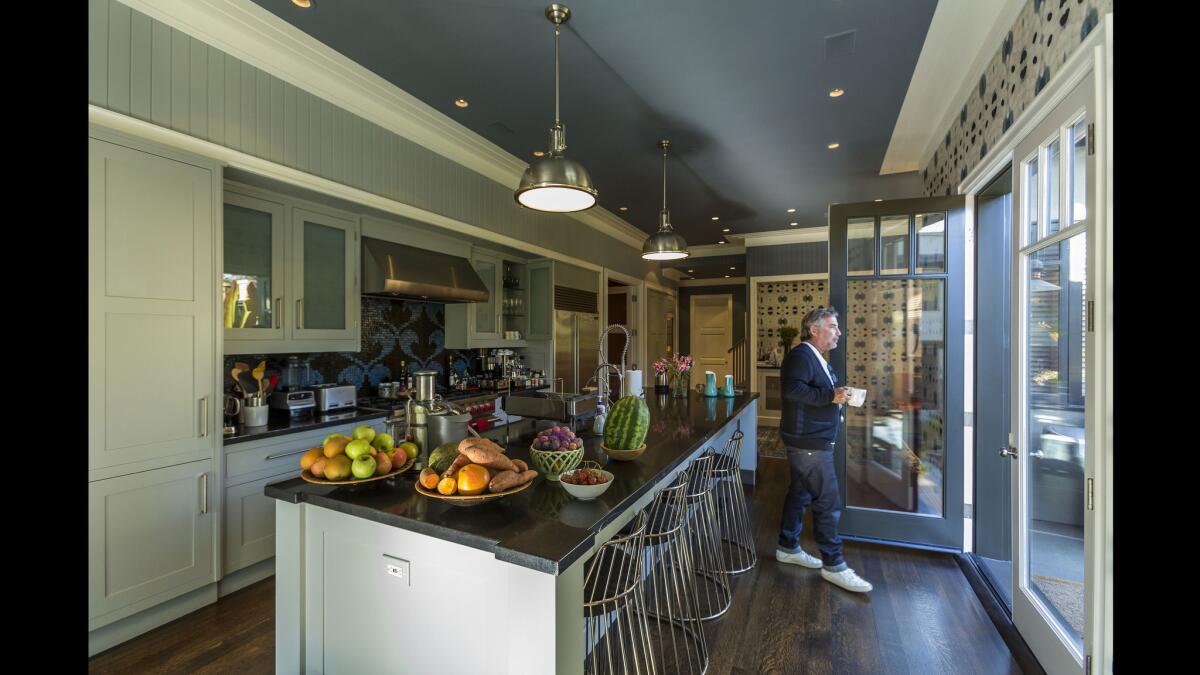 The newly remodeled kitchen features a center island, blue ceilings and graphic wall-coverings from Eskayel. The barstools are from Twentieth.
