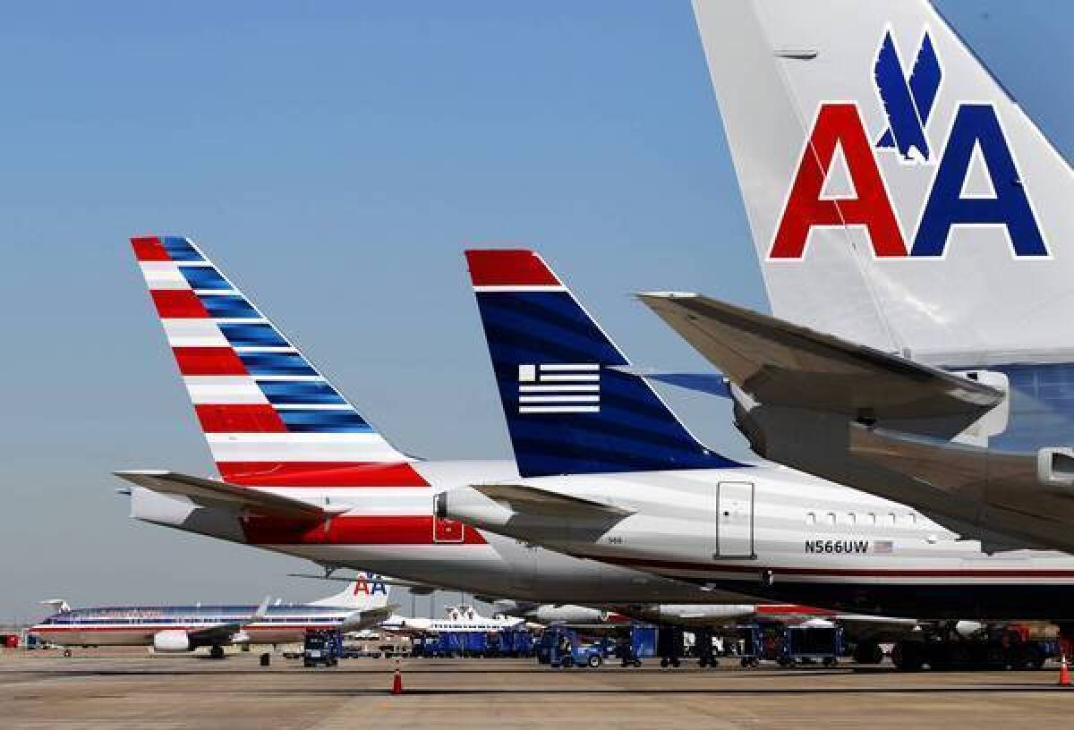 A US Airways plane is parked between two American Airlines planes at Dallas-Fort Worth International Airport. The two airlines merged last month.