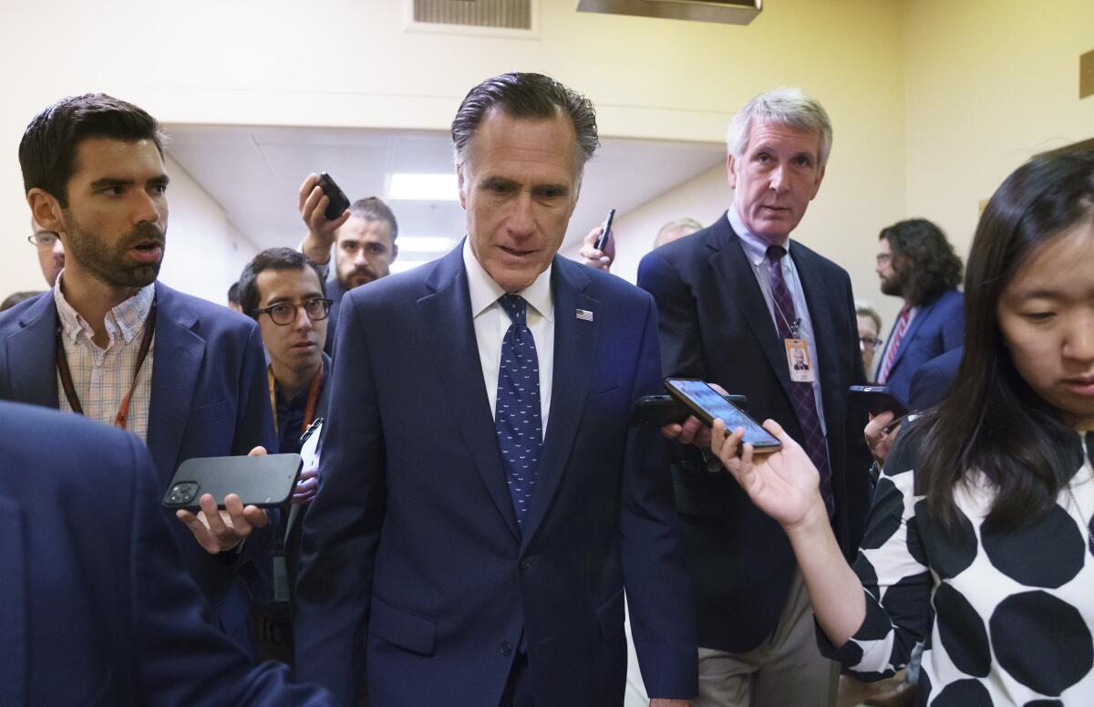 Senator Mitt Romney is surrounded by members of the media