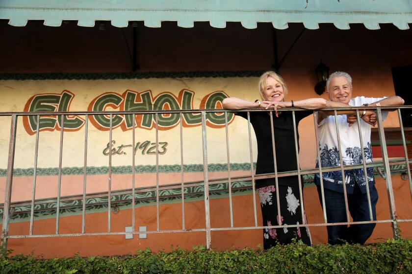 LOS ANGELES, CA - JULY 25, 2023 - Michelle Phillips, 79, of the Mamas & the Papas,and El Cholo owner Ron Salisbury, 90, stand at the entrance of El Cholo Original Restaurant in Los Angeles on July 25, 2023. Phillips has been going to El Cholo for the past 50 years. The restaurant is celebrating it's 100th anniversary this year. (Genaro Molina / Los Angeles Times)