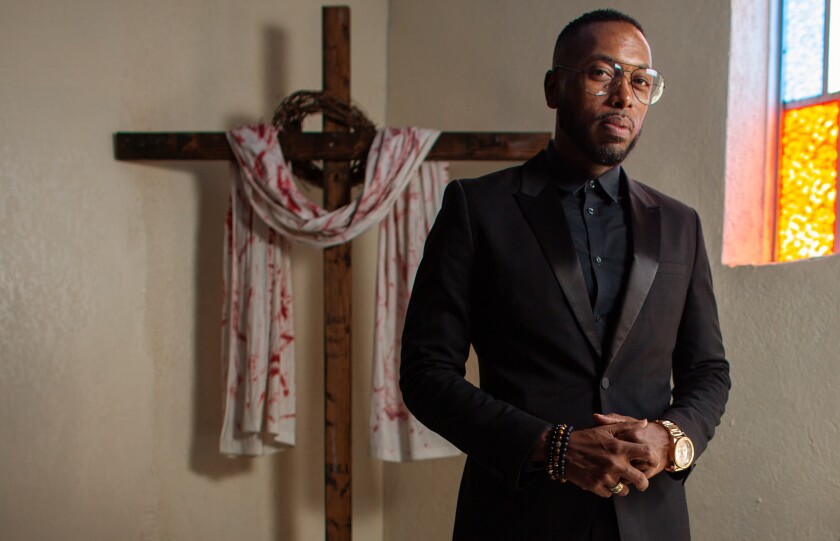 Michael Fisher stands before a cross in the Compton church of the Greater Zion Church Family.