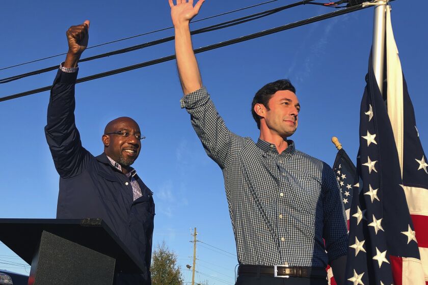 MARIETTA, GA - NOVEMBER 15: Georgia Democratic candidates for U.S. Senate Raphael Warnock, left, and Jon Ossoff, right, gesture toward a crowd during a campaign rally on Sunday, Nov. 15, 2020, in Marietta, Ga.