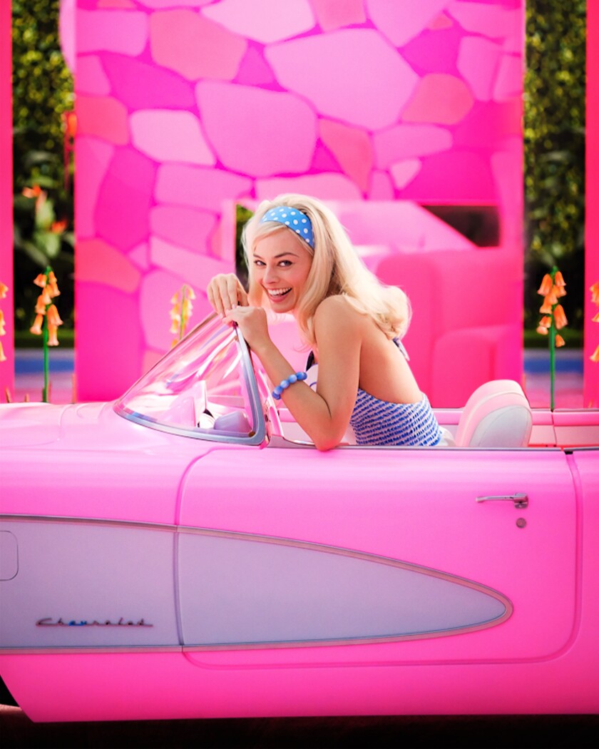 A blonde woman in a blue outfit driving a pink convertible car