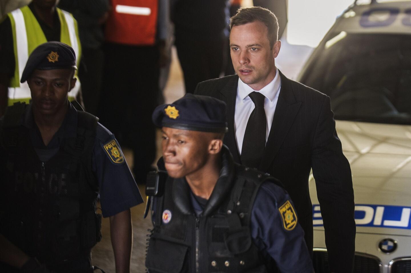 Oscar Pistorius is escorted to a police vehicle to be transported to prison after being sentenced to five years for the negligent killing of his girlfriend Reeva Steenkamp in 2013.