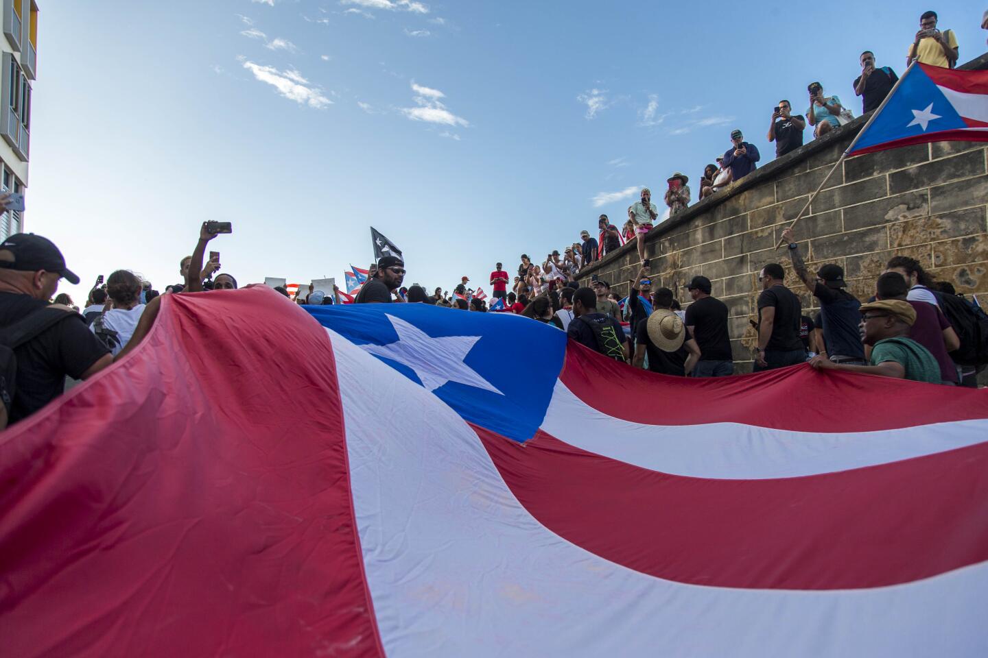 Protesters holding a giant Puerto Rico flag march against Gov. Ricardo Rosello in San Juan.