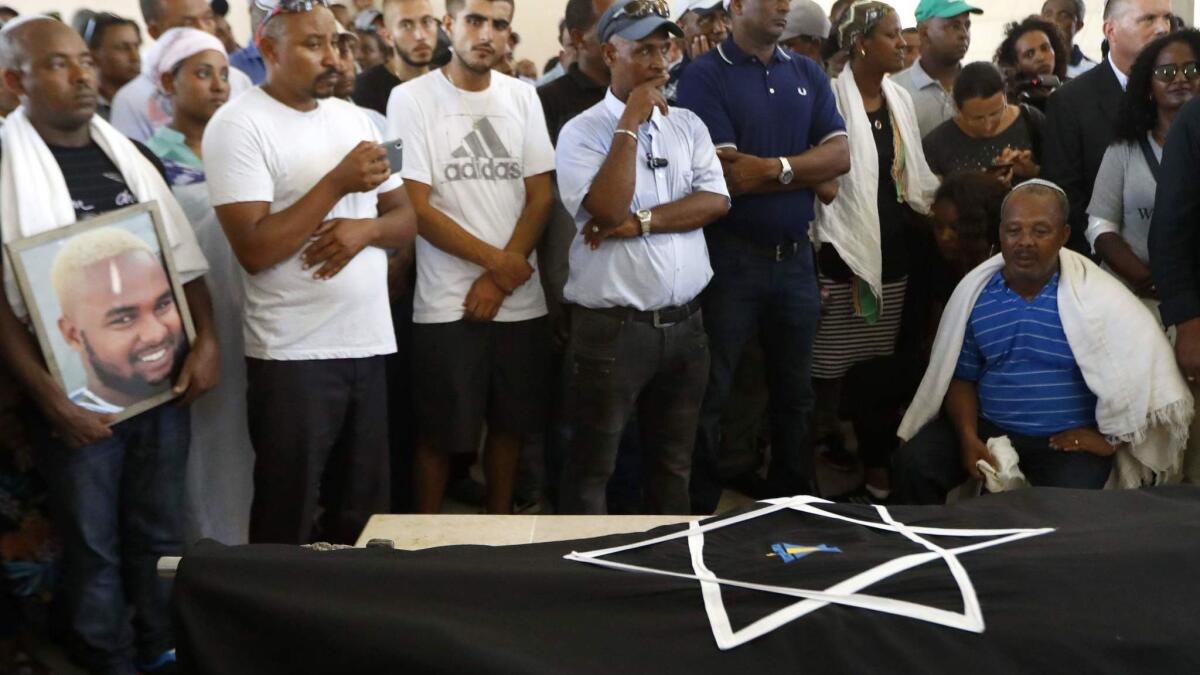 The father of Solomon Teka, an 18-year-old Israeli of Ethiopian descent who was killed by an off-duty Israeli police officer on Sunday, mourns over his son's body during his funeral in the Israeli coastal city of Haifa on Tuesday.