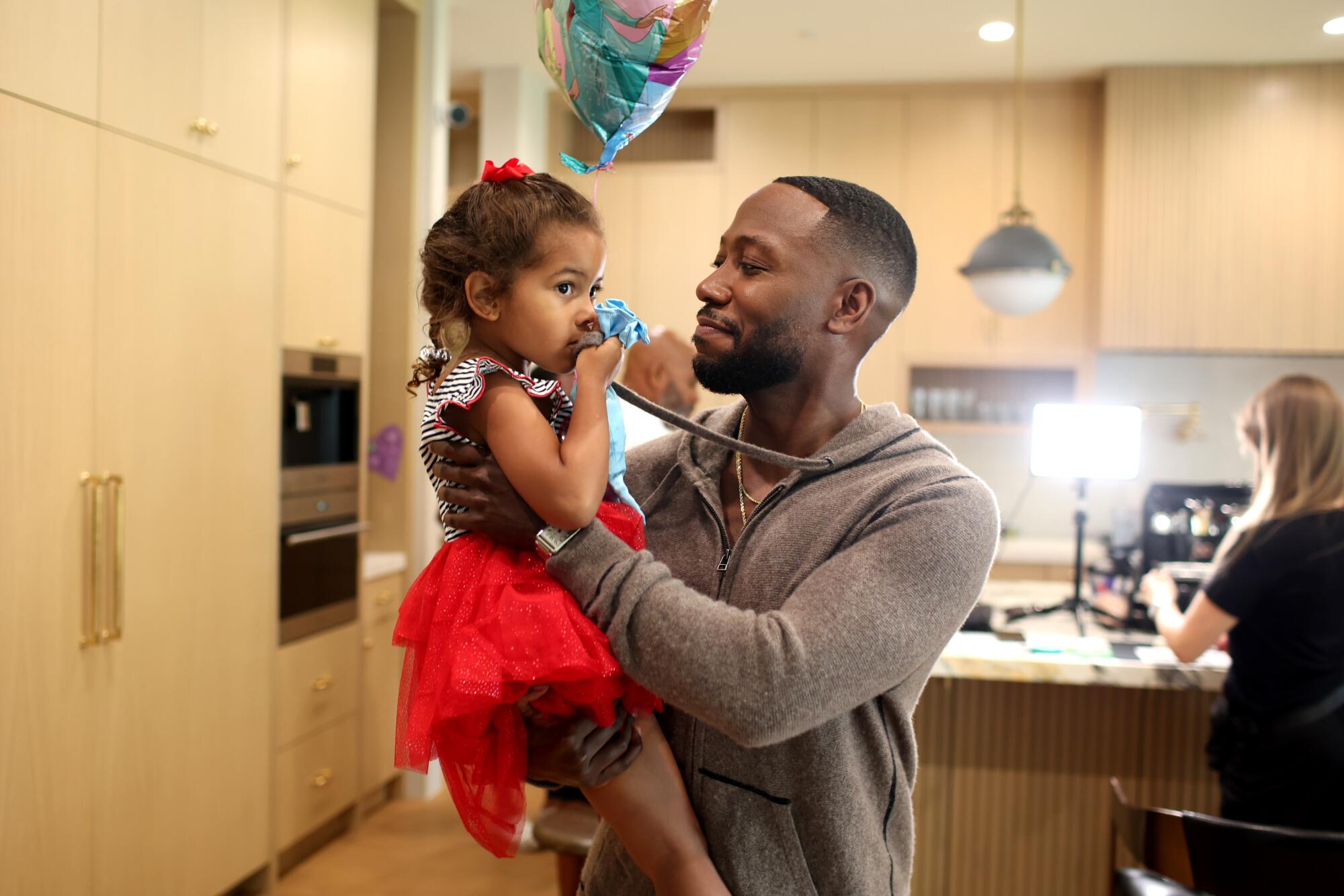 A man holding a little girl in a black and white polka-dot dress with a red skirt.